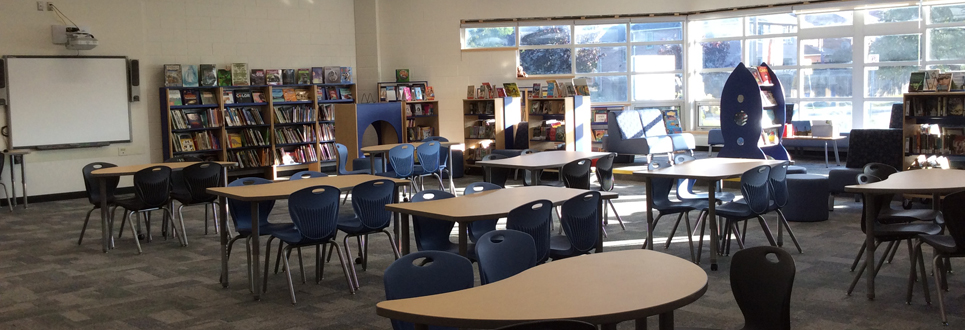 Learning Commons with blue bench seating, book shelves and tables.